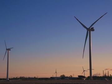 Zwei Windräder vor einem Abendhimmel mit blau-orangem Farbverlauf.