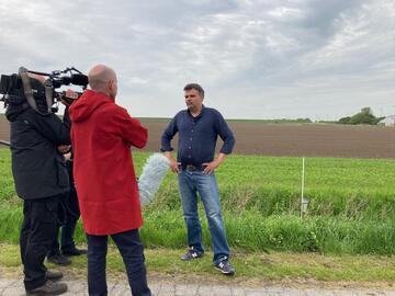 Kameraleute filmen vor einem abgeernteten Feld den Gesellschafter des Dirkshofs, Dag Brodersen.