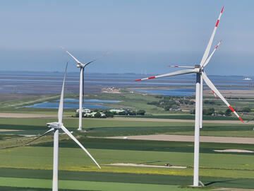 Windräder auf grünen Feldern.