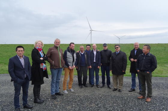Eine Besuchergruppe posiert vor dem Windpark für ein Foto.