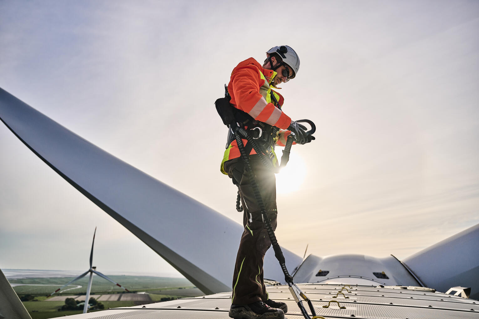 Mann in Sicherheits- und Schutzmontur auf dem Maschinenhaus einer Windkraftanlage