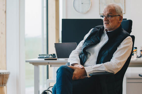 Geschäftsführer Dirk Ketelsen sitzt auf einem Schreibtischstuhl, im Hintergrund ein heller Büroraum mit einem Schreibtisch und einer Trommel vor dem Fenster.