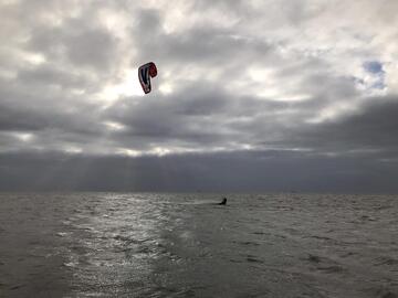 Aufnahme eines Kiters auf dem Wasser vor bewölktem Himmel.