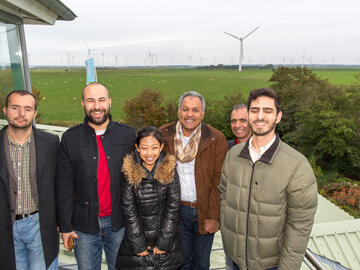 Besucher lachen bei einer Führung durch den Windpark in die Kamera.
