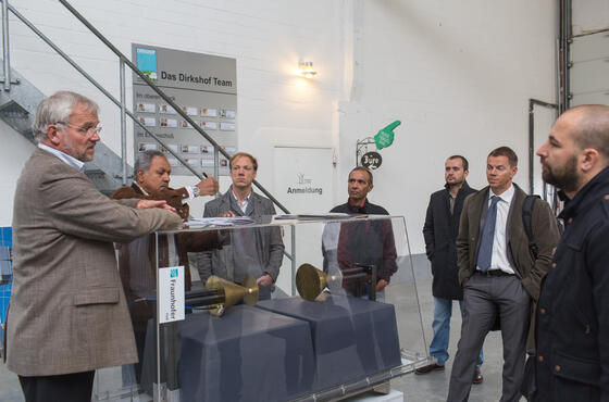 Mann erklärt Besucher bei einer Führung durch den Windpark etwas in einer Halle.