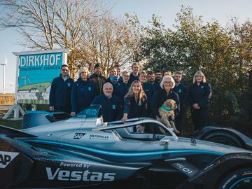 Ein Rennwagen steht am Eingang des Dirkshofs, das Team des Dirkshofs posiert dahinter für ein Gruppenfoto.