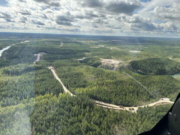 Aus dem Fenster eines kleinen Passagierflugzeugs fotografiert sieht man dichte grüne Wälder, dazwischen Flüsse.